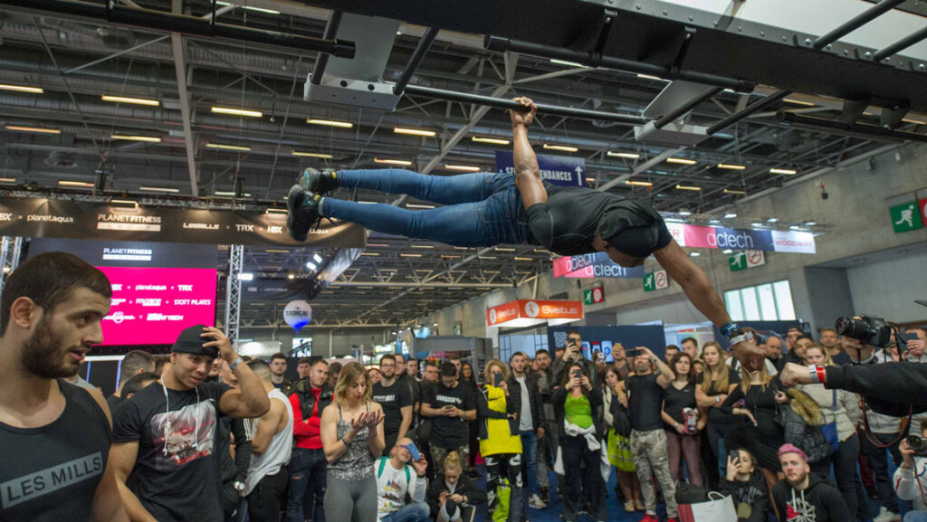 Trade Show Entertainer hanging off bar with one hand and crowd shocked